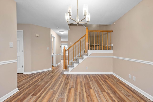 staircase with hardwood / wood-style floors and a notable chandelier