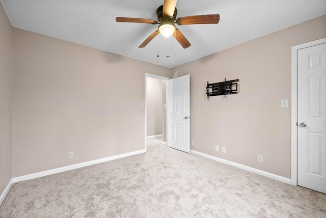 empty room featuring ceiling fan, light colored carpet, and a textured ceiling