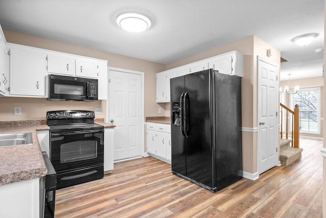 kitchen featuring sink, light hardwood / wood-style flooring, white cabinetry, black appliances, and a chandelier