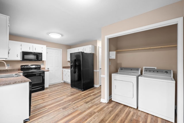 kitchen with sink, washing machine and dryer, white cabinetry, light hardwood / wood-style floors, and black appliances