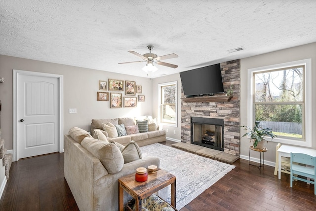 living room with ceiling fan, a healthy amount of sunlight, dark wood-type flooring, and a fireplace