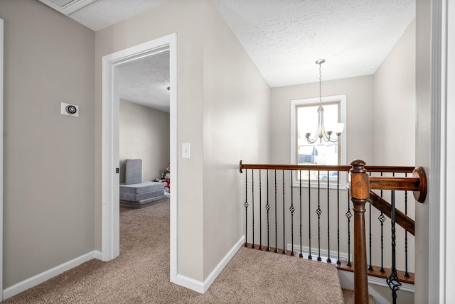 corridor with carpet, an inviting chandelier, and a textured ceiling