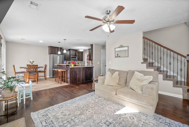 living room with a textured ceiling, dark wood-type flooring, and ceiling fan