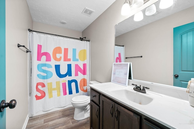 bathroom featuring hardwood / wood-style flooring, vanity, a textured ceiling, and toilet