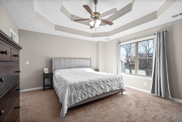 carpeted bedroom with ceiling fan, a textured ceiling, and a tray ceiling