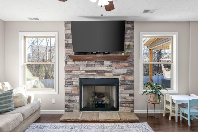 living room featuring dark hardwood / wood-style flooring, a textured ceiling, a fireplace, and ceiling fan