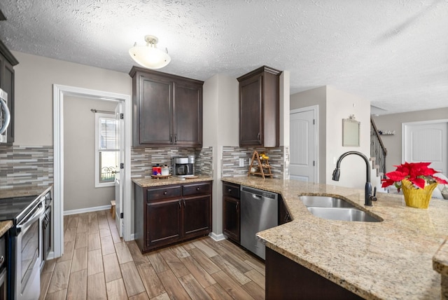 kitchen featuring appliances with stainless steel finishes, sink, decorative backsplash, light stone counters, and light hardwood / wood-style floors