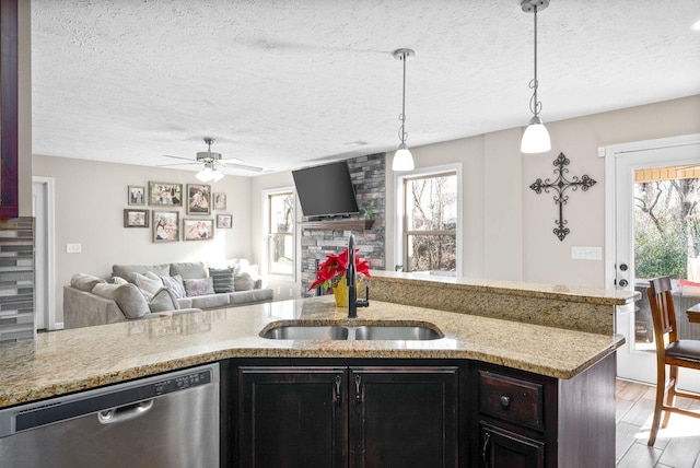 kitchen featuring light stone countertops, pendant lighting, sink, and stainless steel dishwasher