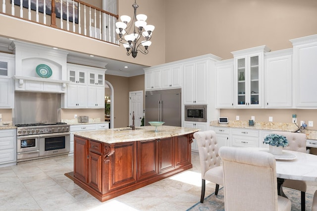 kitchen with an island with sink, built in appliances, and white cabinets