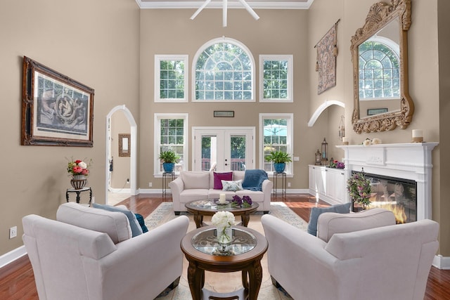 living room with a high ceiling, wood-type flooring, crown molding, and french doors