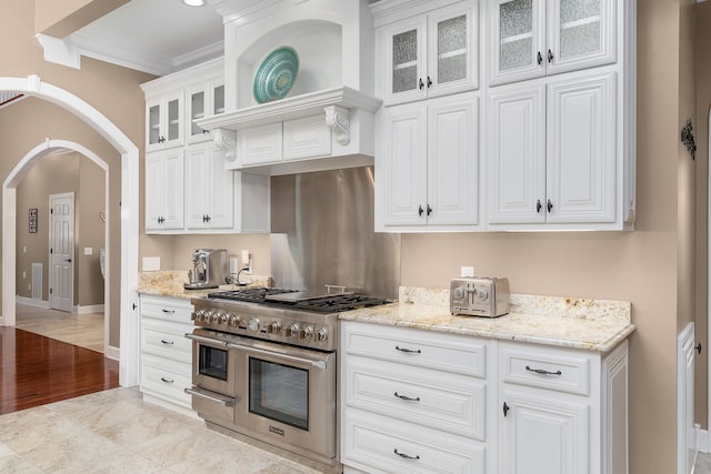 kitchen with white cabinetry, light stone countertops, and range with two ovens