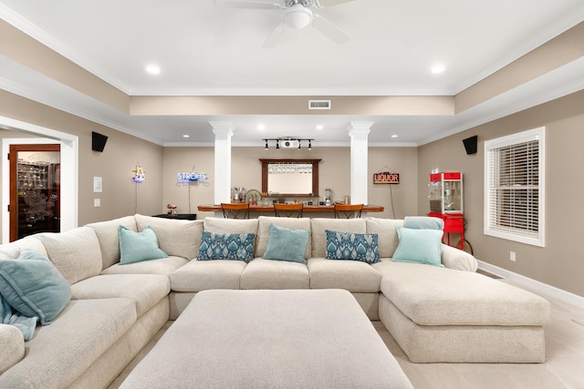 living room with crown molding, a tray ceiling, and decorative columns