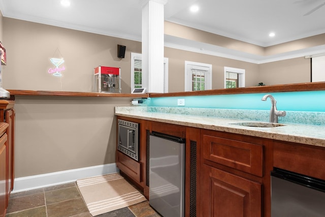 kitchen featuring crown molding, stainless steel microwave, sink, and light stone counters