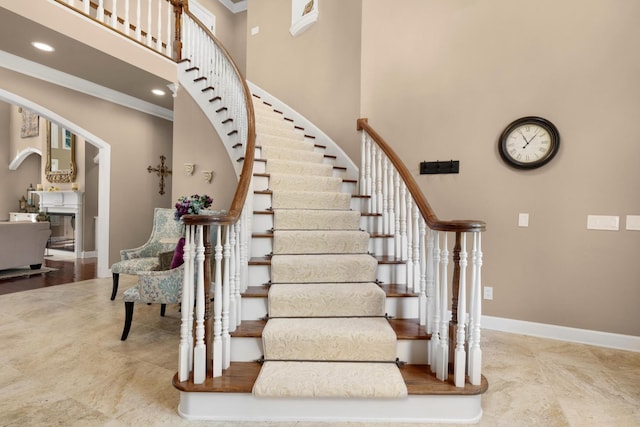 staircase with ornamental molding and a towering ceiling