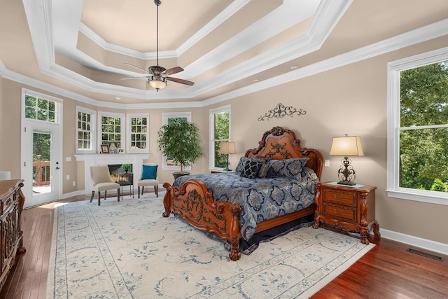 bedroom with crown molding, wood-type flooring, a tray ceiling, ceiling fan, and access to exterior