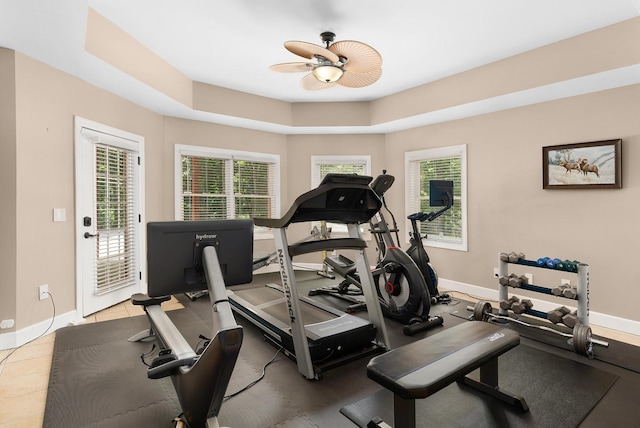 exercise room featuring a tray ceiling and ceiling fan