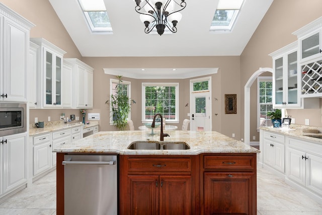 kitchen with sink, vaulted ceiling with skylight, white cabinets, and appliances with stainless steel finishes