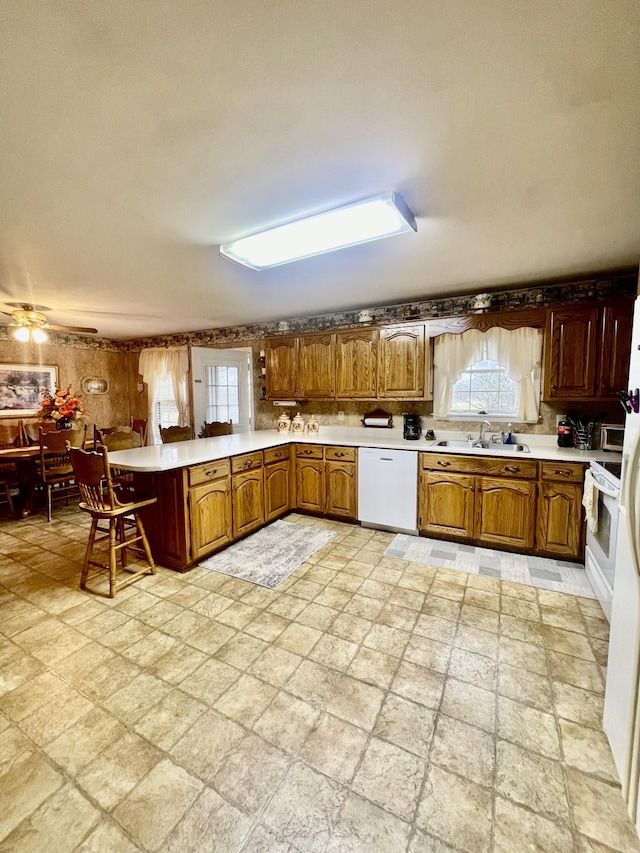 kitchen with dishwasher, sink, a breakfast bar area, ceiling fan, and kitchen peninsula