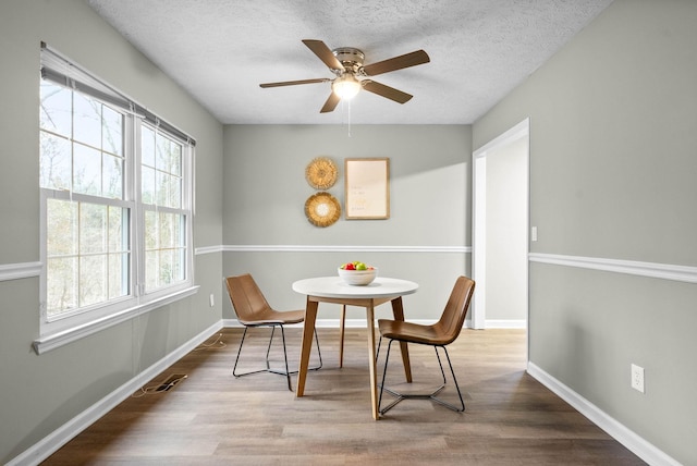 dining room with ceiling fan, hardwood / wood-style floors, and a textured ceiling