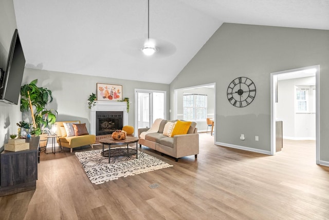 living room with ceiling fan, high vaulted ceiling, and light wood-type flooring