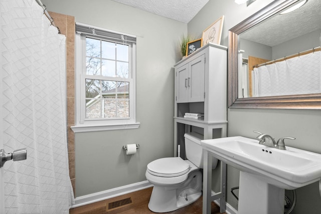 bathroom with sink, hardwood / wood-style flooring, walk in shower, toilet, and a textured ceiling