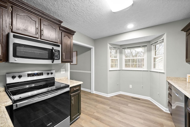 kitchen featuring dark brown cabinetry, light hardwood / wood-style flooring, stainless steel appliances, and a textured ceiling