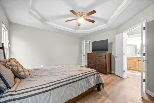 bedroom with a tray ceiling, a textured ceiling, and light wood-type flooring