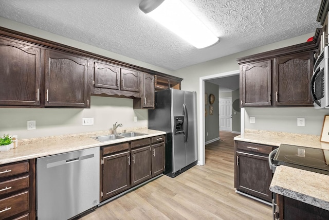 kitchen with dark brown cabinetry, sink, a textured ceiling, light wood-type flooring, and stainless steel appliances