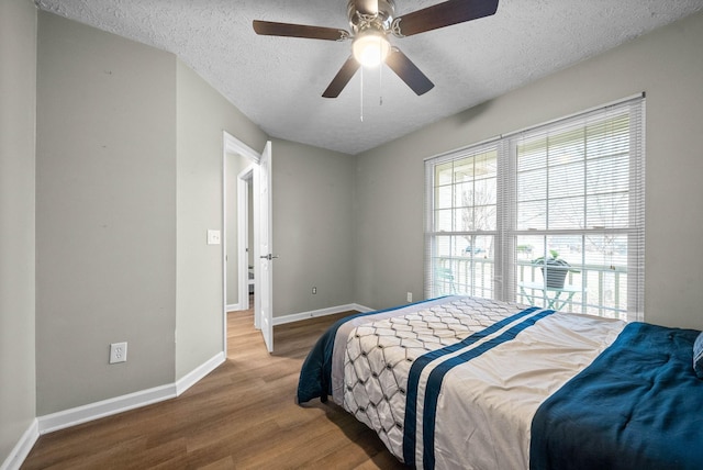 bedroom featuring ceiling fan, hardwood / wood-style floors, and a textured ceiling