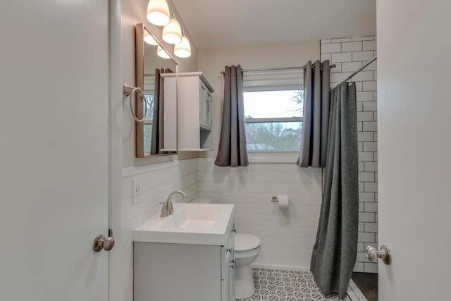 bathroom featuring toilet, a shower with curtain, tile patterned flooring, vanity, and tile walls