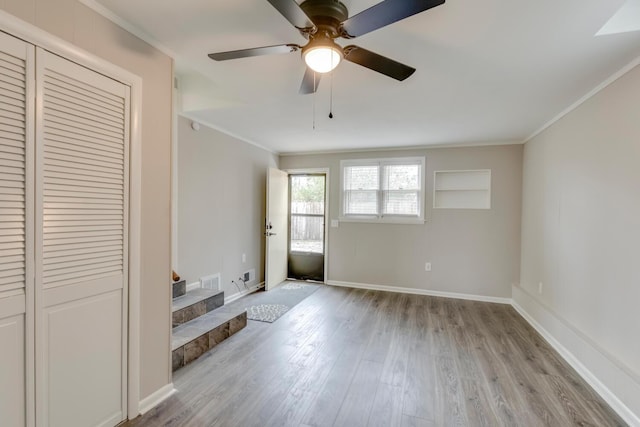 interior space featuring baseboards, ornamental molding, ceiling fan, and wood finished floors