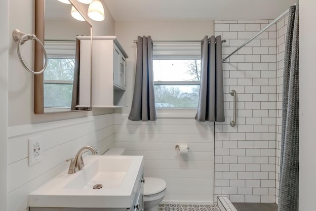 bathroom featuring toilet, a shower stall, tile walls, and vanity