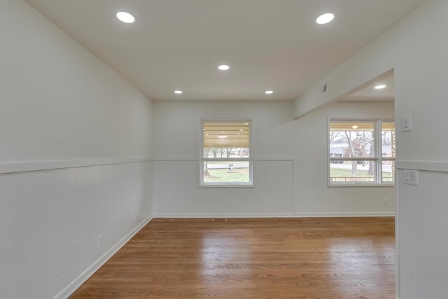 spare room with recessed lighting, a wainscoted wall, and wood finished floors