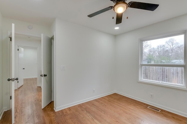 empty room featuring light wood-style floors, baseboards, visible vents, and a ceiling fan