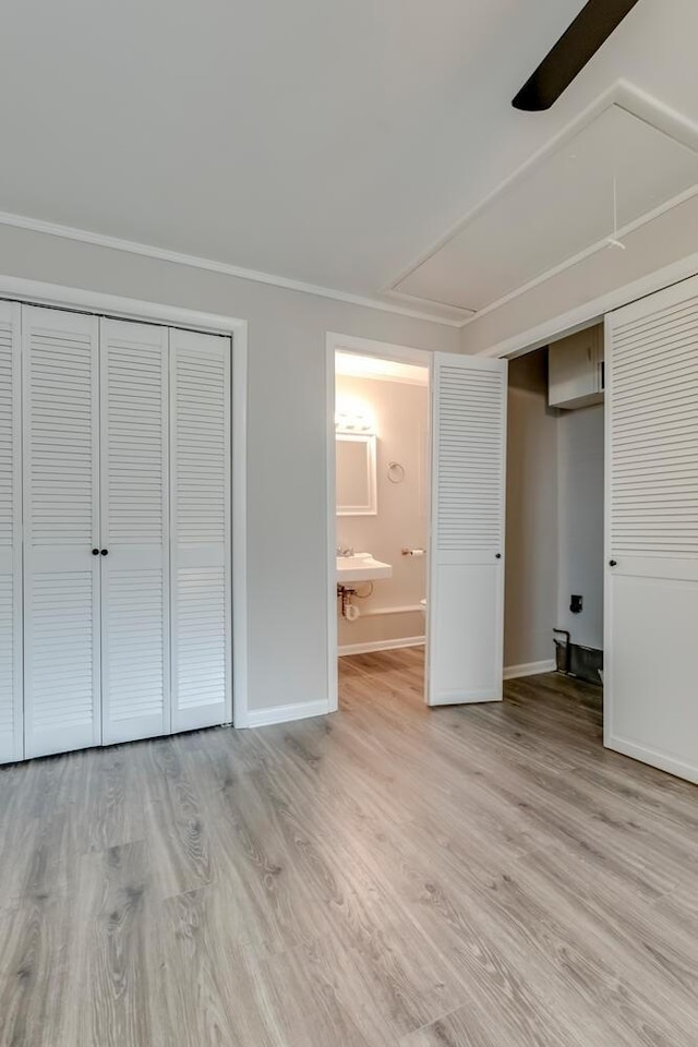 unfurnished bedroom with light wood-style floors, ensuite bath, and baseboards