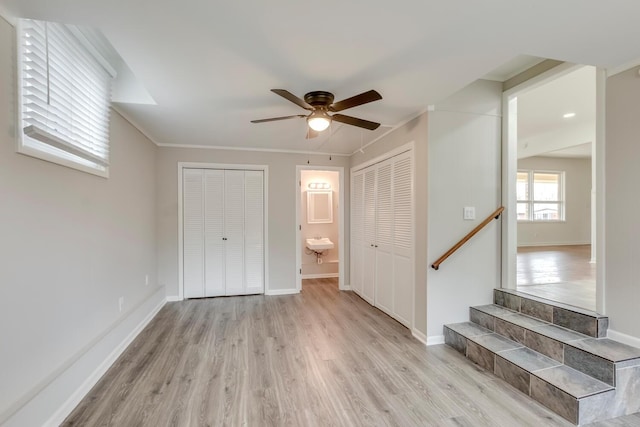 interior space featuring crown molding, light wood-type flooring, ceiling fan, and baseboards