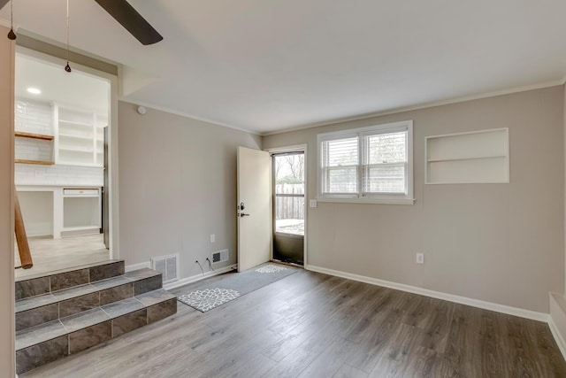 interior space featuring visible vents, crown molding, baseboards, and wood finished floors