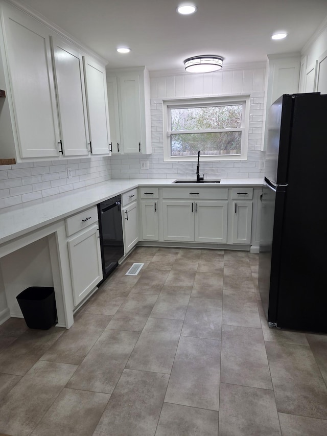 kitchen with black appliances, white cabinetry, visible vents, and a sink