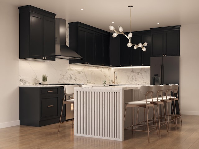 kitchen featuring wall chimney range hood, sink, a kitchen island, a kitchen bar, and light wood-type flooring