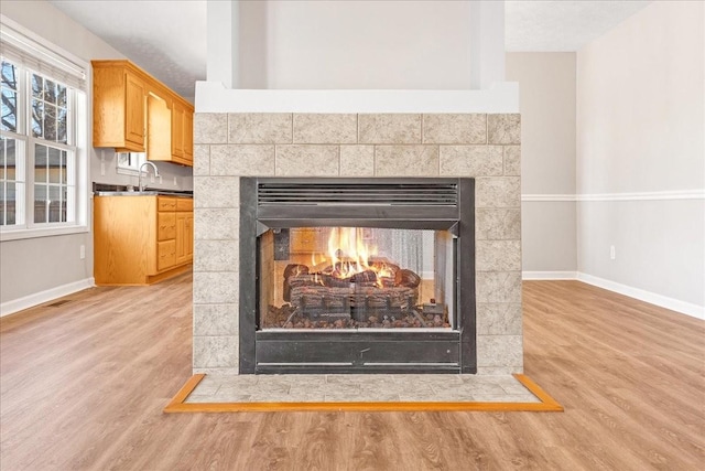 interior details featuring wood-type flooring, a tiled fireplace, and sink