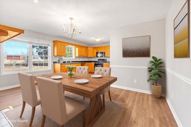 dining space with sink, a chandelier, and light hardwood / wood-style floors