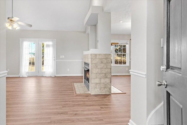 living room featuring a fireplace, ceiling fan, and light wood-type flooring