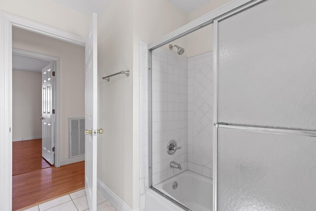 bathroom with tile patterned flooring and bath / shower combo with glass door