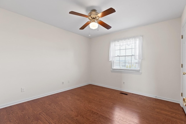 empty room featuring dark wood-type flooring and ceiling fan