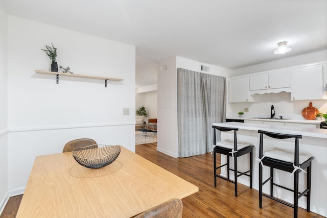 kitchen with white cabinetry, a kitchen bar, dark wood-type flooring, and sink