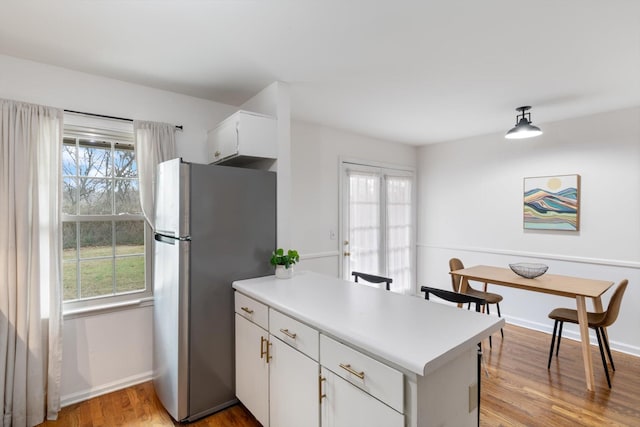 kitchen with white cabinetry, a wealth of natural light, light hardwood / wood-style floors, and stainless steel refrigerator