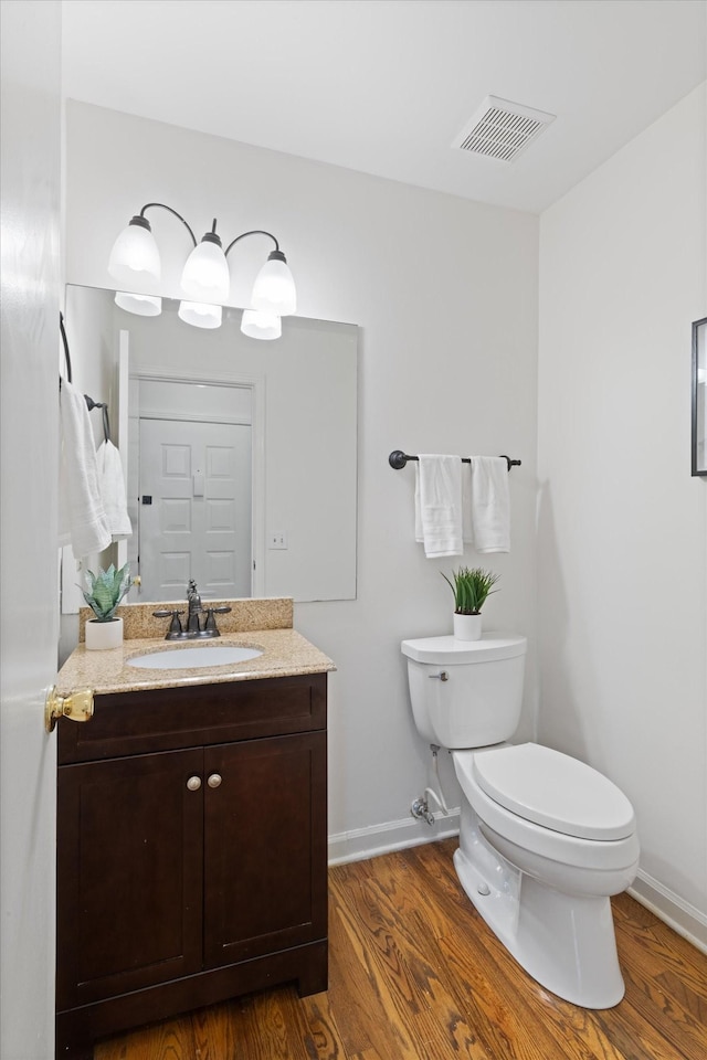 bathroom with wood-type flooring, vanity, and toilet