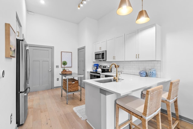 kitchen featuring sink, decorative light fixtures, appliances with stainless steel finishes, a kitchen breakfast bar, and kitchen peninsula