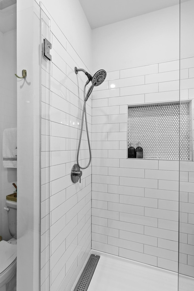 bathroom with toilet and a tile shower