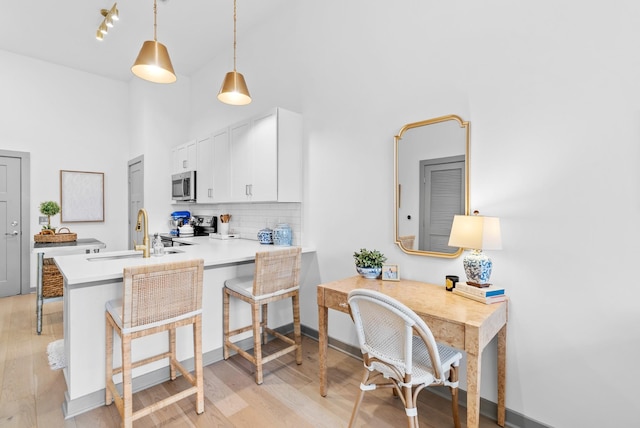 kitchen with appliances with stainless steel finishes, a breakfast bar, white cabinetry, sink, and kitchen peninsula